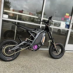 SURRON Light Bee X Electric Bike 2024. Key features include:  Type: Electric dirt bike. Motor: Electric. Top Speed: 45 mph +. Range: 20 to 60 miles per charge, depending on conditions. Recharge Time: 2.5 to 3.5 hours. Brakes: 4-piston hydraulic disc brakes, front and rear. Age restriction: At least 16 years old (may vary depending on local laws). Legality: Primarily designed for off-road use, not street-legal. Customization: Features aftermarket parts such as Bomberzz.