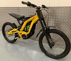 yellow 2024 SURRON Light Bee X Electric Bike. It's a lightweight electric dirt bike designed for off-road use.  Key features include:  Electric Powertrain: Equipped with a 60V removable lithium-ion battery. Lightweight Frame: Forged alloy frame, total weight around 47kg. Off-road Capability: Suitable for various terrains. Speed: Can reach up to 47 mph (73 km/h). Range: A range of up to 80 miles on a single charge, depending on conditions. Wheels: 19-inch spoke wheels with alloy hubs. Tires: Front and rear 70/100-19 CST tires.
