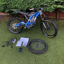 blue 2024 SURRON Light Bee X Electric Bike. Key features include:  Type: Electric dirt bike, blending elements of a dirt bike and mountain bike. Performance: Top speed of 47 mph (73 km/h), with a range of 40-80 miles depending on conditions. Motor: 5400W. Weight: 47 kg plus battery. Features: Upgraded components like RockShox suspension. Battery: Can be fully charged in 3-4 hours.