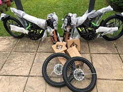 two Surron Light Bee X electric bikes and two spare tires. Helpful information:  The Surron Light Bee X is a popular electric bike known for its innovative technology and attractive design.  It has a peak power of 6000W (8HP).  It has a cruising range of 75 km and a top speed of 75 km/h.  It is popular with riders of all ages and abilities.  The Surron Light Bee X is not street legal in some areas and is primarily designed for off-road use.  To ride a Surron electric bike, the rider must be at least 16 years old.