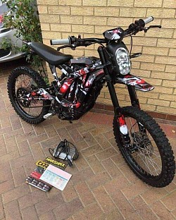 SUR-RON Light Bee X electric dirt bike. Key features include:  Type: Electric dual-sport dirt bike. Power: 60V, with over 6kW peak power. Battery: Removable Panasonic Lithium-ion. Top Speed: Around 45-50 mph after unlocking the speed limiter. Range: Up to 80 miles on a single charge, depending on conditions. Weight: 47 kg plus the battery. Street Legal: Can be made street legal with the addition of mirrors and registration. Graphics: Features custom Marshmx CA22 graphics.