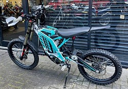 SUR-RON Light Bee X electric dirt bike. Key features include:  Type: Electric dirt bike designed primarily for off-road use.  Speed: Top speed of approximately 45 mph (72 km/h). Some models may reach up to 55-60 mph.  Range: Can travel around 40-60 miles on a single charge, depending on usage and conditions.  Motor: Equipped with a 6kW mid-motor.  Battery: Typically uses a 60V battery system.  Weight: Weighs around 57 kg.  Legality: Generally not street-legal due to the lack of functional pedals.