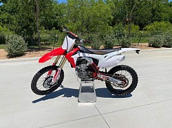 2016 Honda CRF450R dirt bike. Key details include:  Manufacturer: Honda Model: CRF450R Year: 2016 Tires: Dunlop Features: Fuel injection, optional electric start Performance: Considered a benchmark in its class Handling: Good overall, but less forgiving of mistakes Modifications: May include aftermarket parts like a water pump cover and seat cover