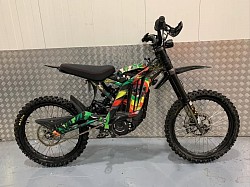 The image shows a Surron Light Bee X, an electric dirt bike designed for off-road use. Key features include:  Motor: PMSM motor with 5,400 rpm max Battery: 60V 40Ah Lithium Range: 20 to 60 miles depending on the mode Top speed: 47 mph (75 km/h) Charge time: 2.5 to 3.5 hours Weight: 123 lbs (56 kg) Brakes: Upgraded 4 Piston Brakes